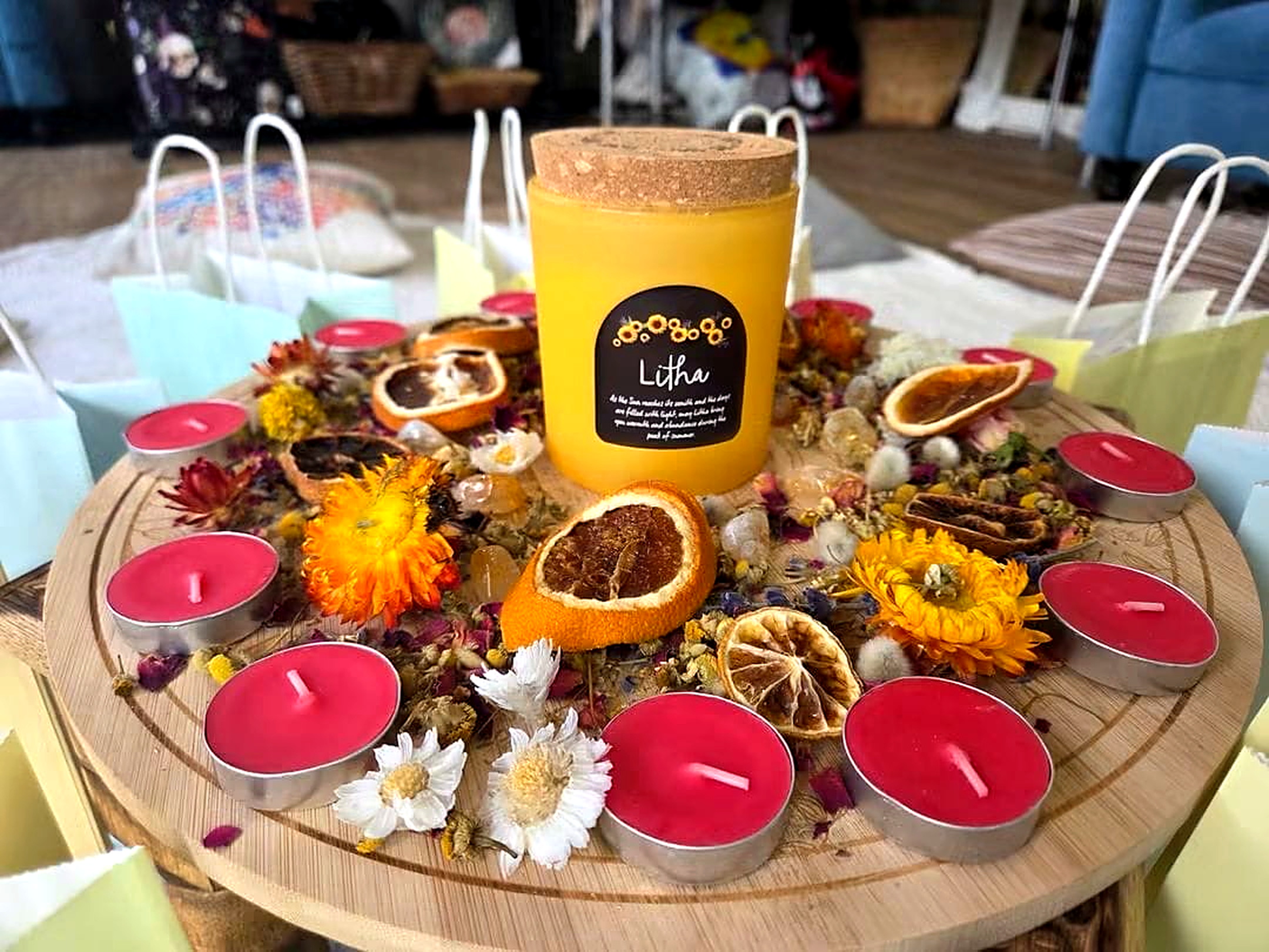 A Litha candle surrounded by flowers, citrus and candlelight for a seasonal gathering